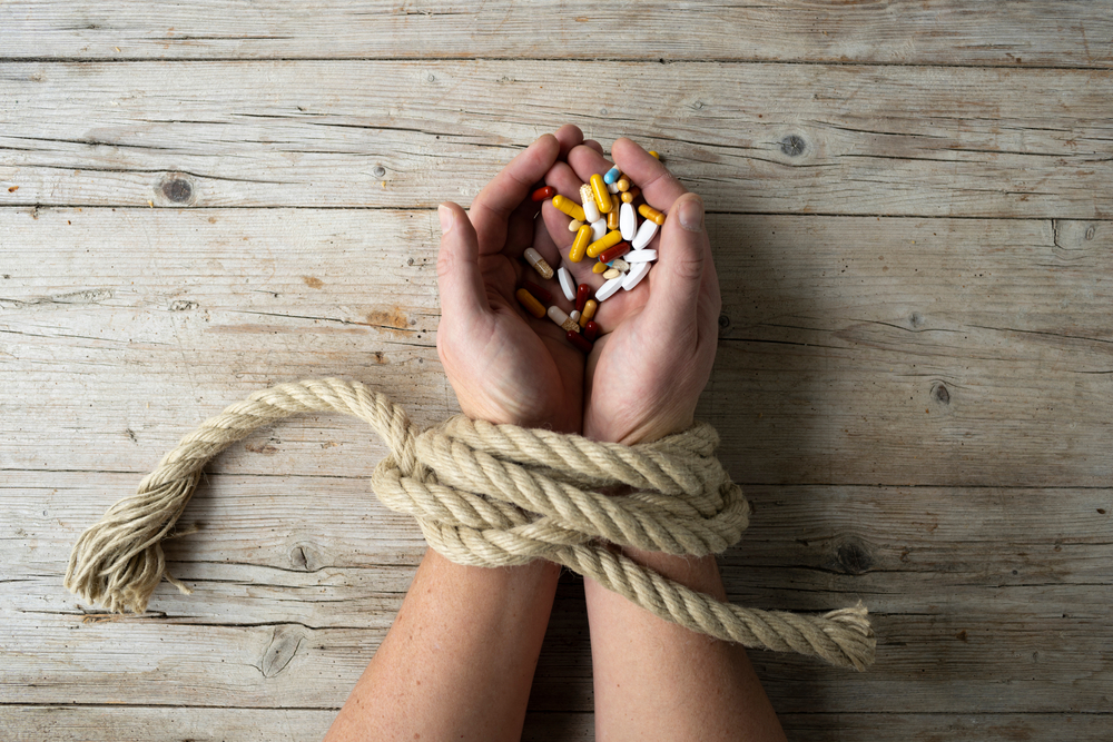 Hands tied to opioids to show addiction