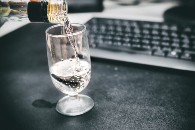 Drunk,At,Work.,Pouring,A,Glass,Of,Vodka.,Defocused,Office Alcohol at work showing functional alcoholism