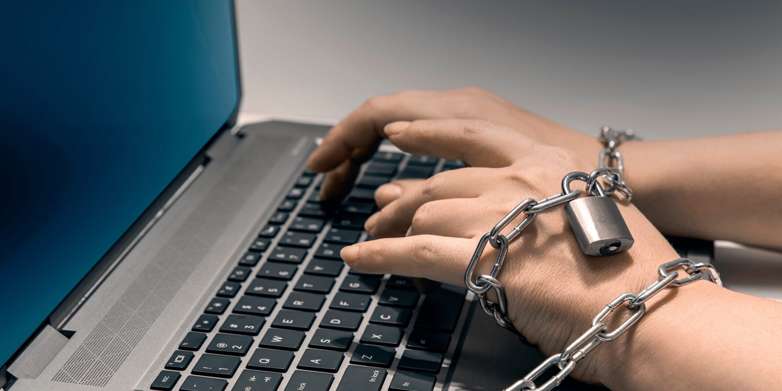 Hands,Shackled,In,Chains,Typing,On,A,Laptop,Keyboard.,The Individual Shackled to a laptop to show online gambling addiction