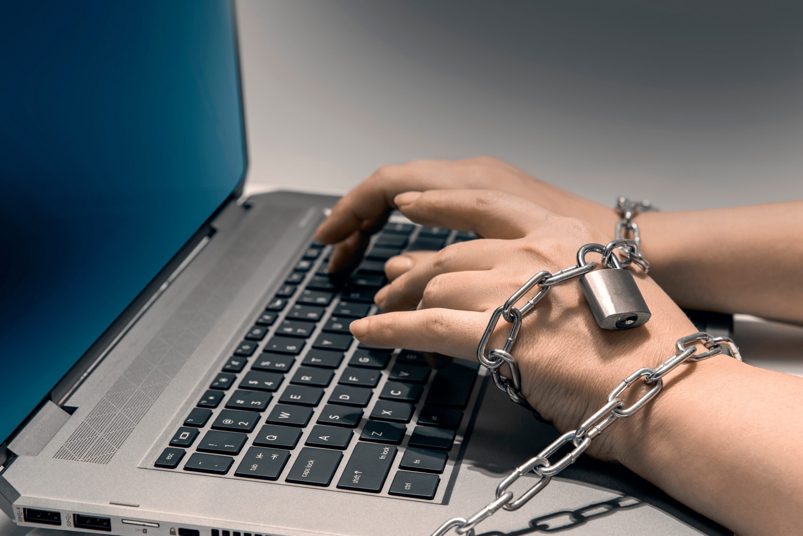 Individual Shackled to a laptop to show online gambling addiction